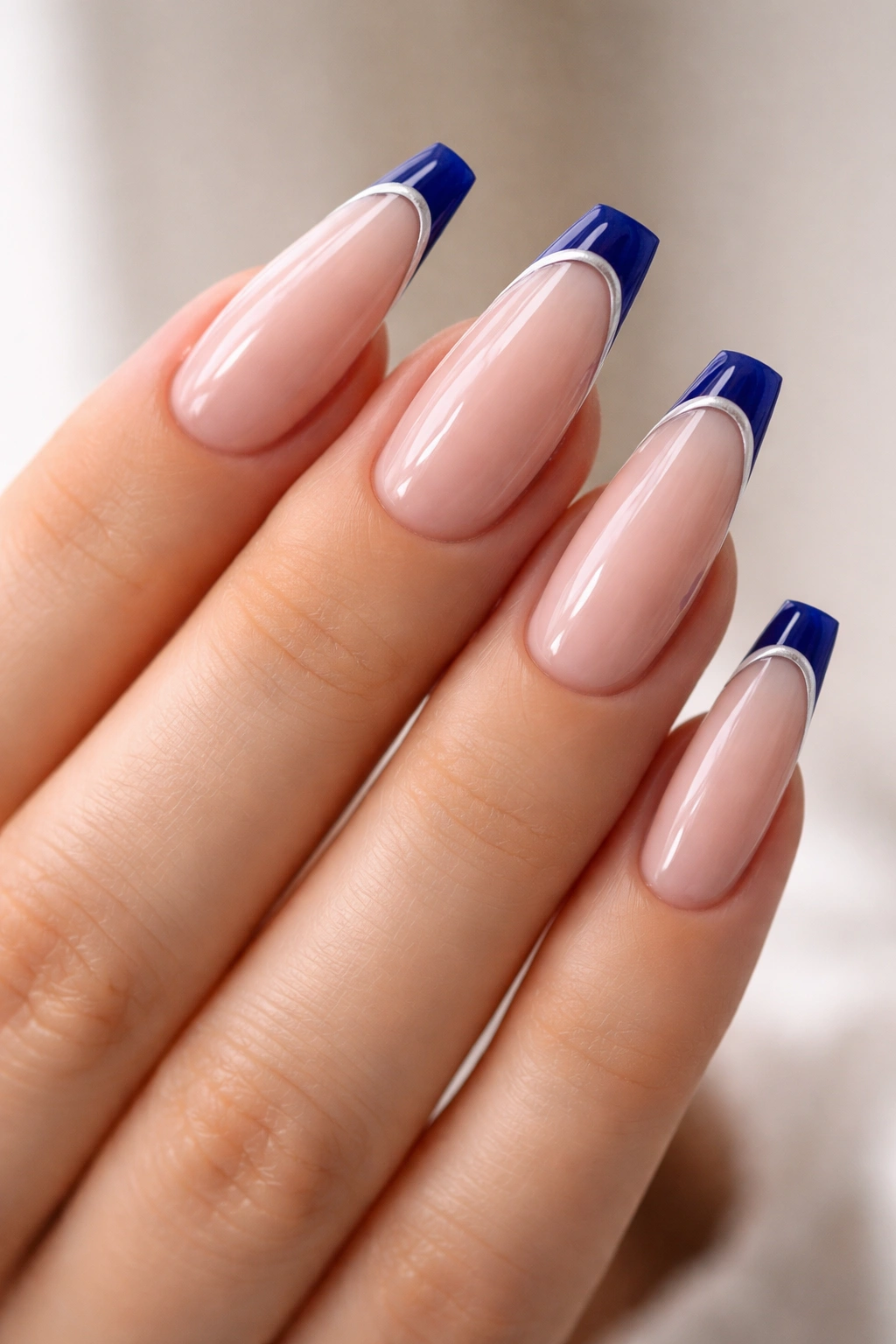 Close-up of cobalt micro-French coffin nails with a thin cobalt tip on a nude base.