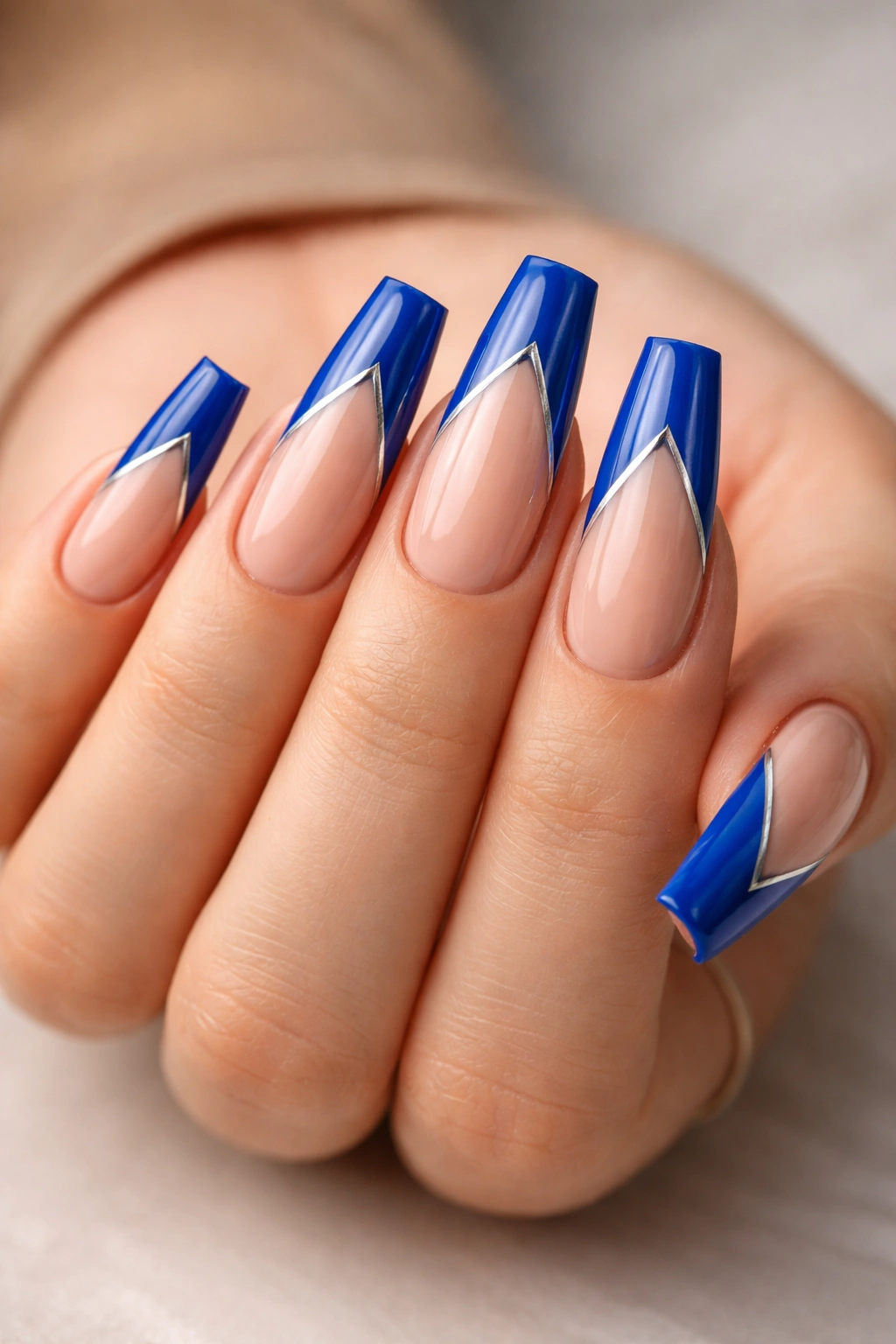 Close-up of cobalt blue V-tip coffin nails with a slender silver stripe, perfectly symmetrical.