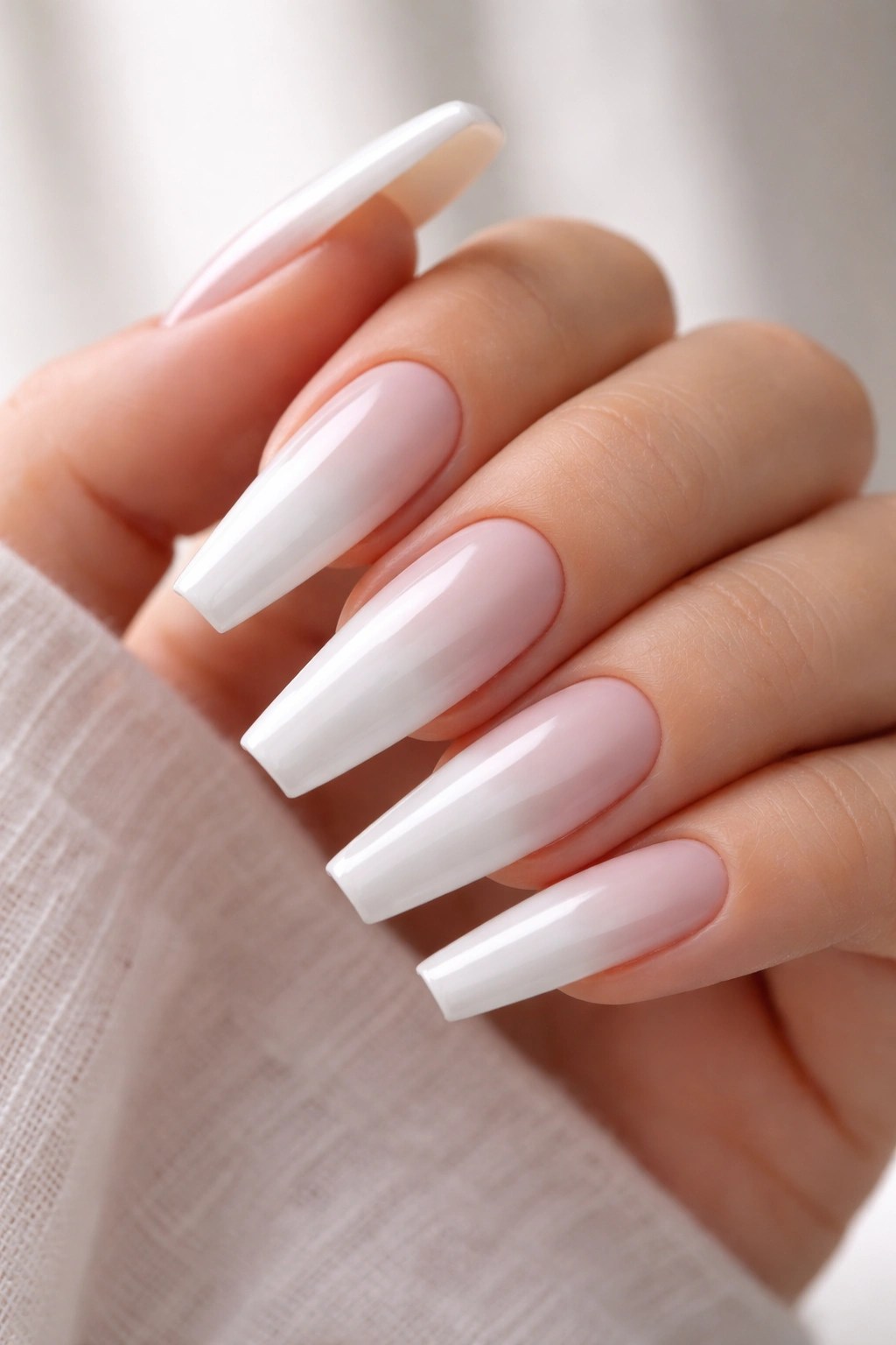 Close-up of nails with white center and tip and nude sidewalls on long ballerina nails.