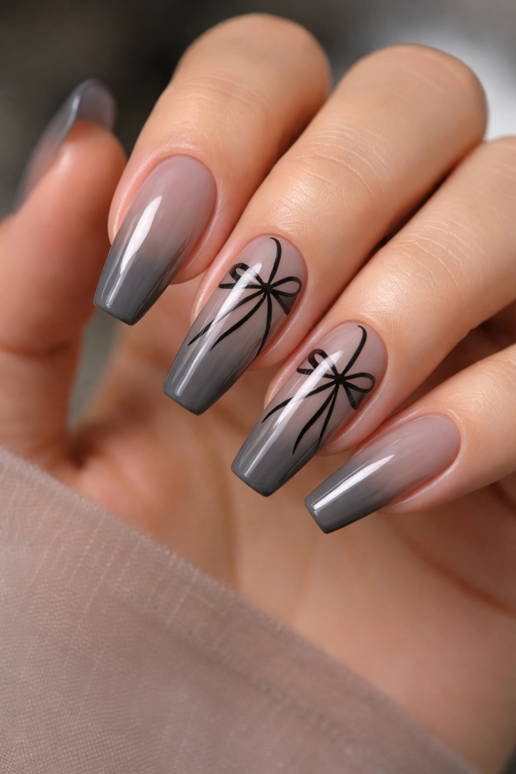Close-up of coffin nails with sheer charcoal base and black ribbon accents