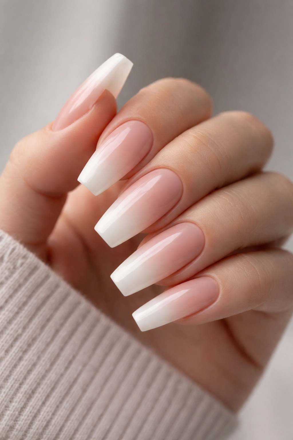 Coffin nails with pink-beige to white ombré fade on a hand, no harsh line