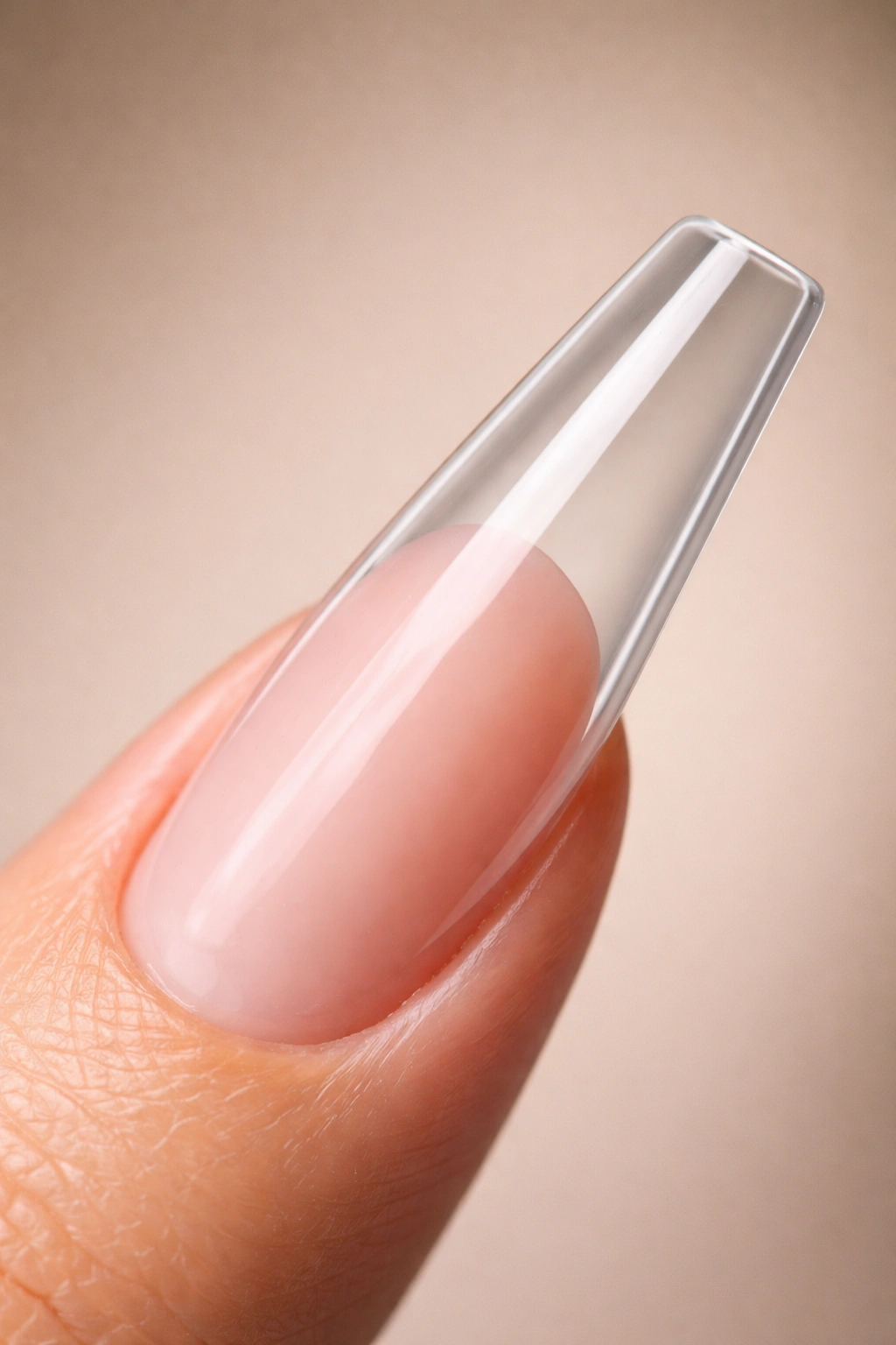 Close-up of a long coffin acrylic nail with a clean tapered apex on a neutral background
