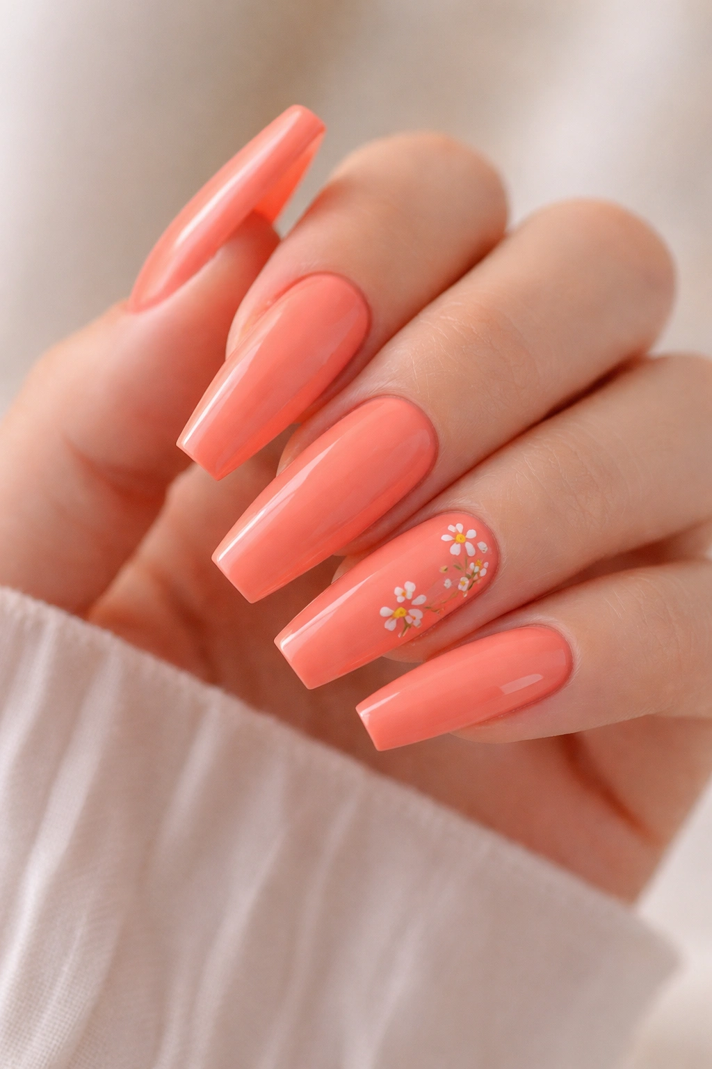 Coral-orange nails with tiny white floral accents on a couple of nails