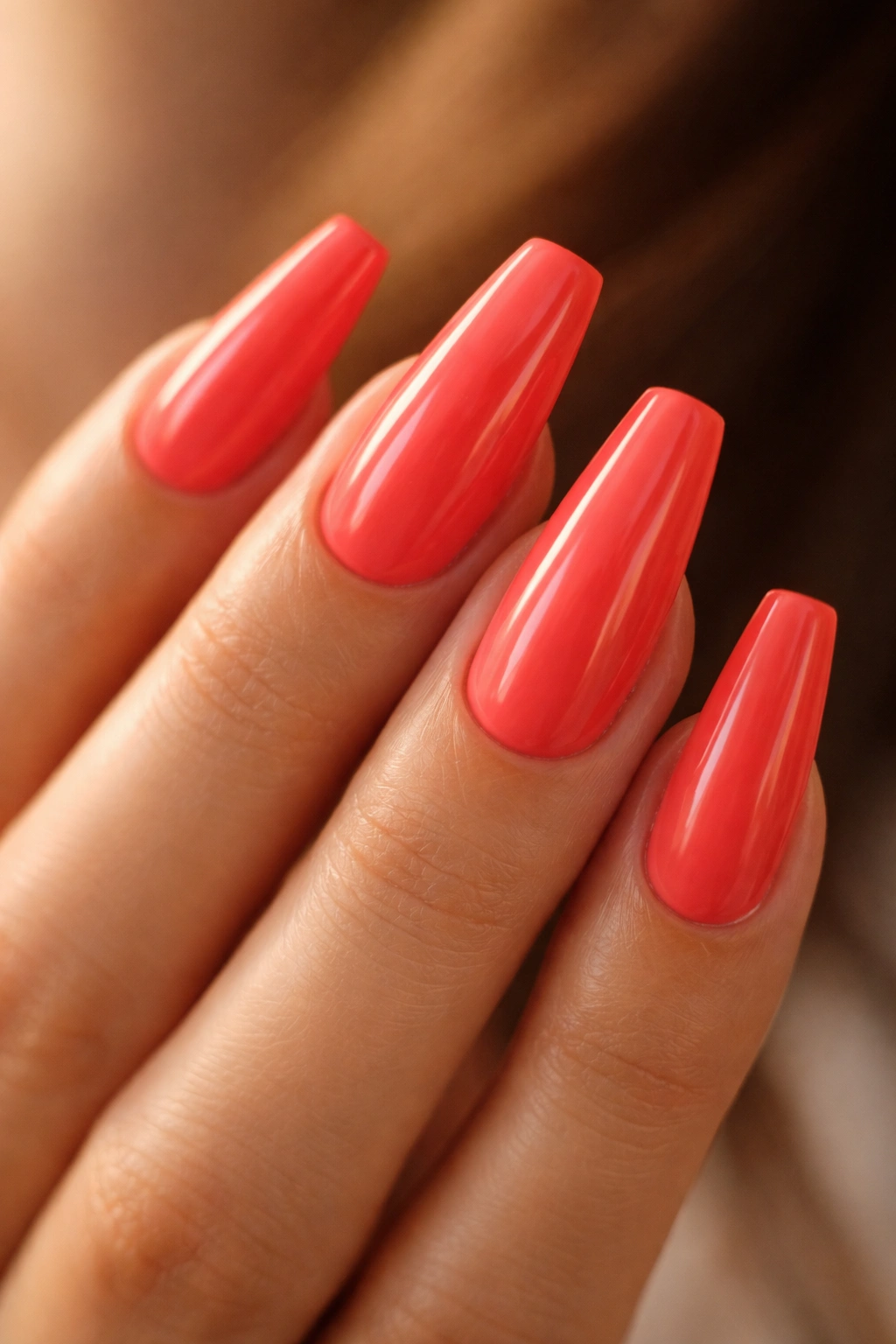 Close-up of coral-red coffin nails with creamy gloss