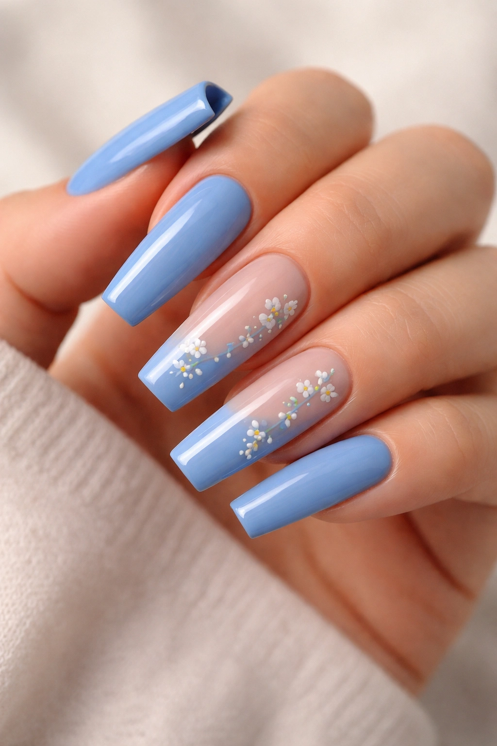 Close-up of cornflower blue coffin nails with tiny white floral accents on two nails.