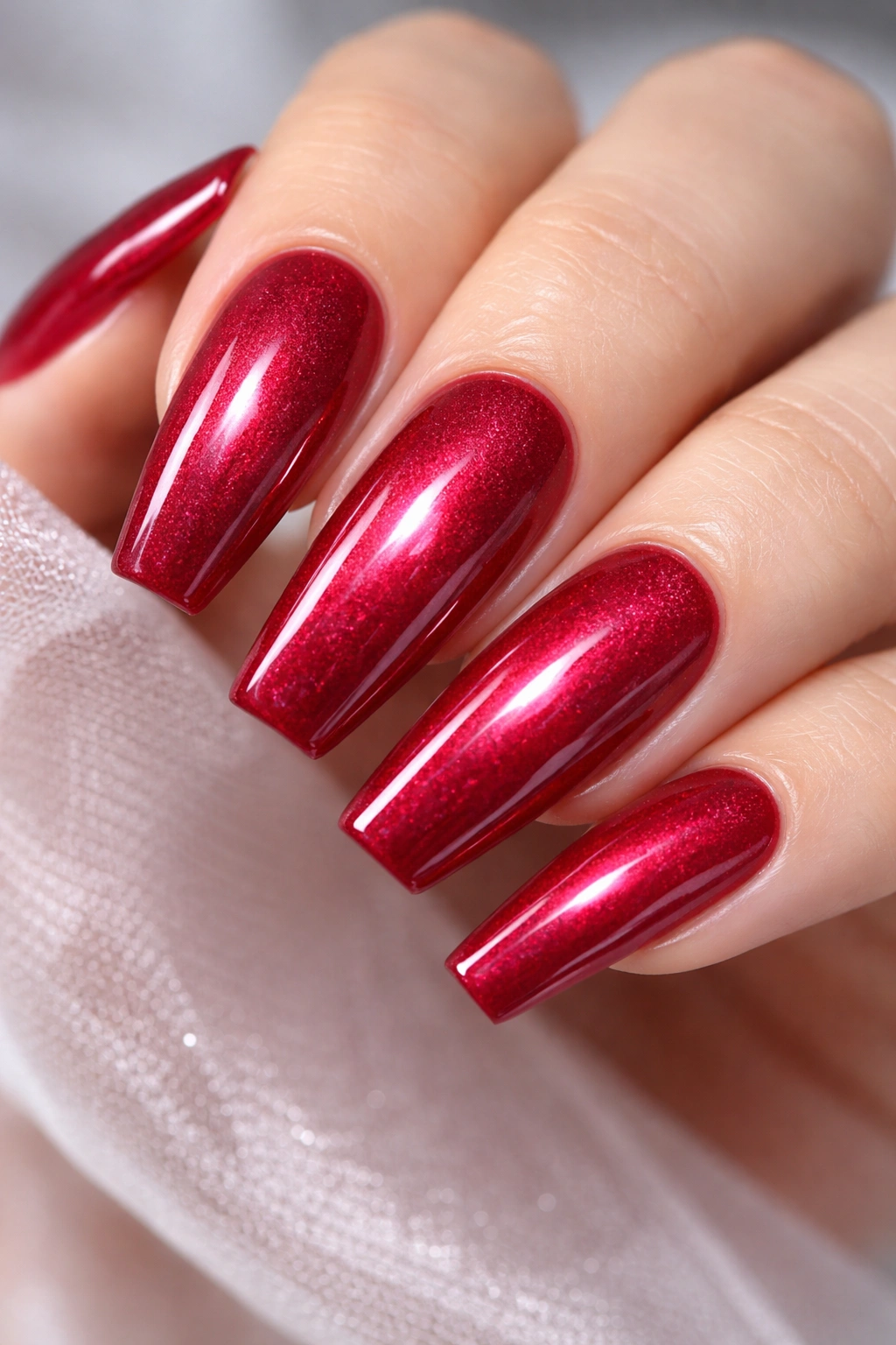 Close-up of cranberry coffin nails with fine shimmer and glassy top coat