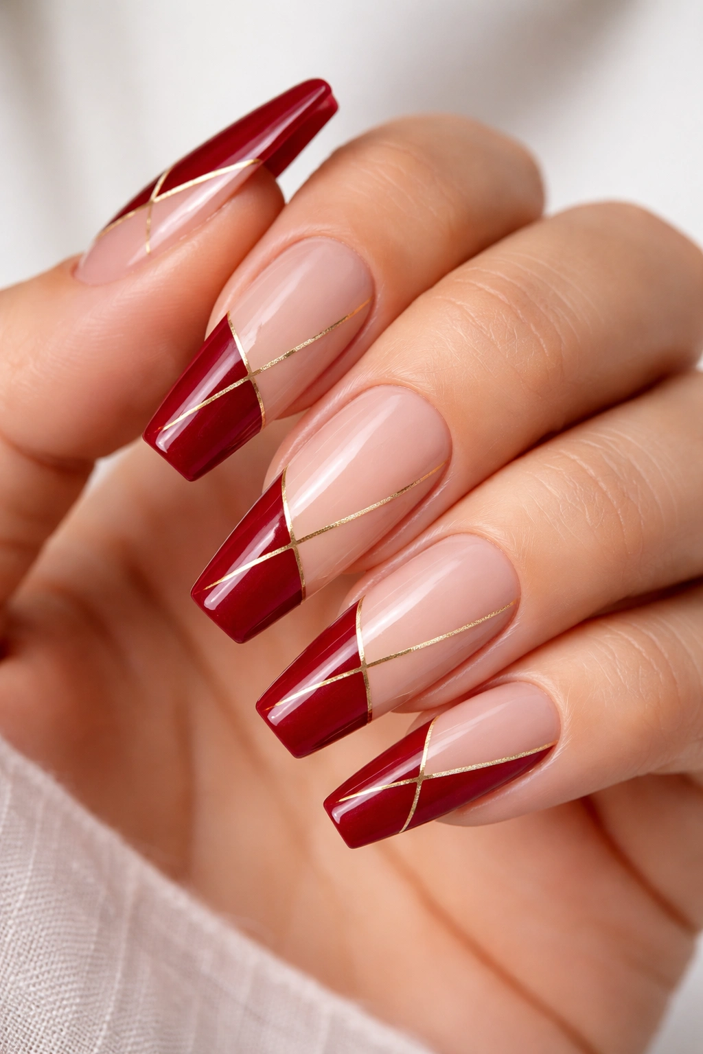 Crimson and nude color-block coffin nails with gold lines, photorealistic