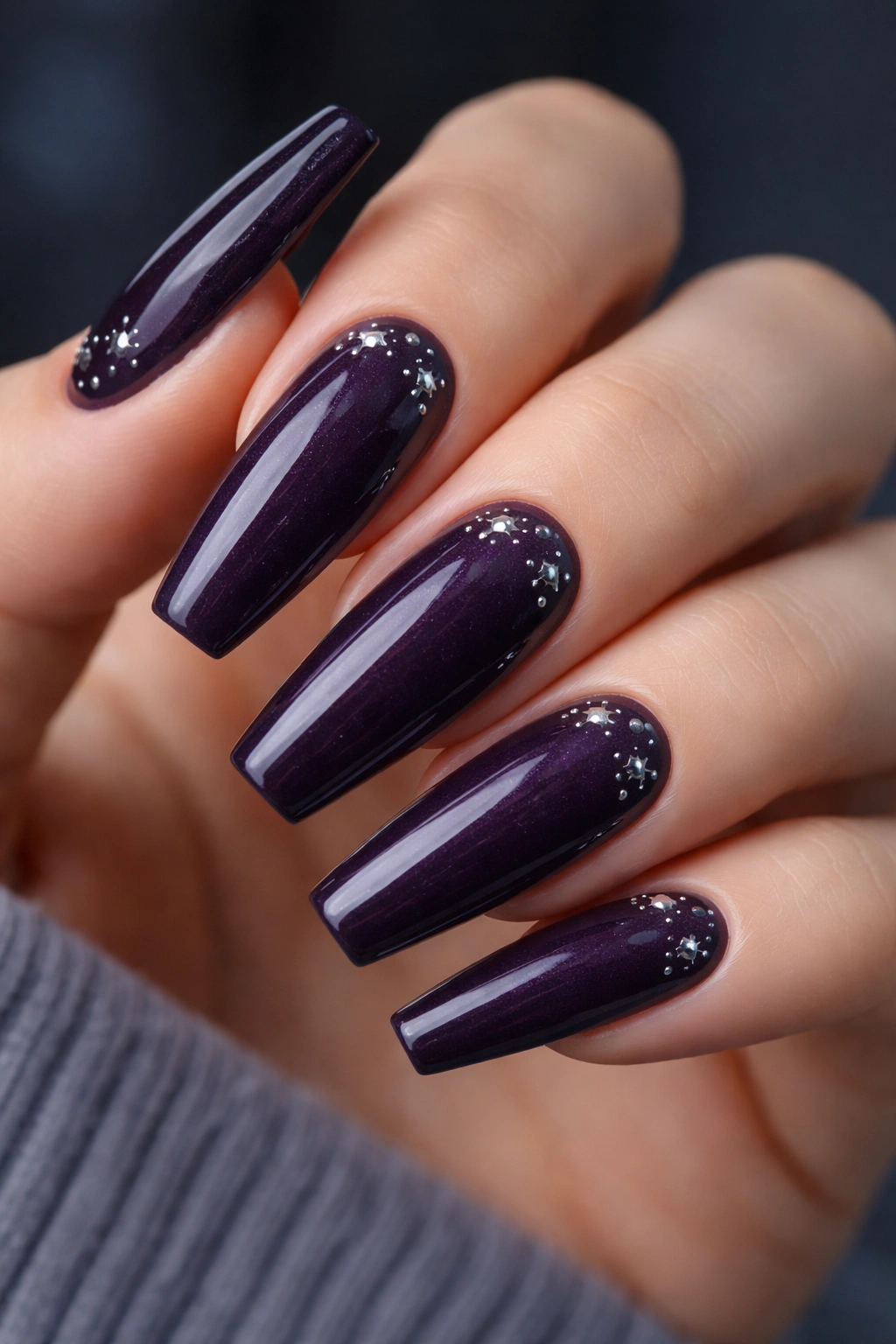 Close-up of Dark Amethyst nails with tiny silver stars on a deep purple base, glossy finish