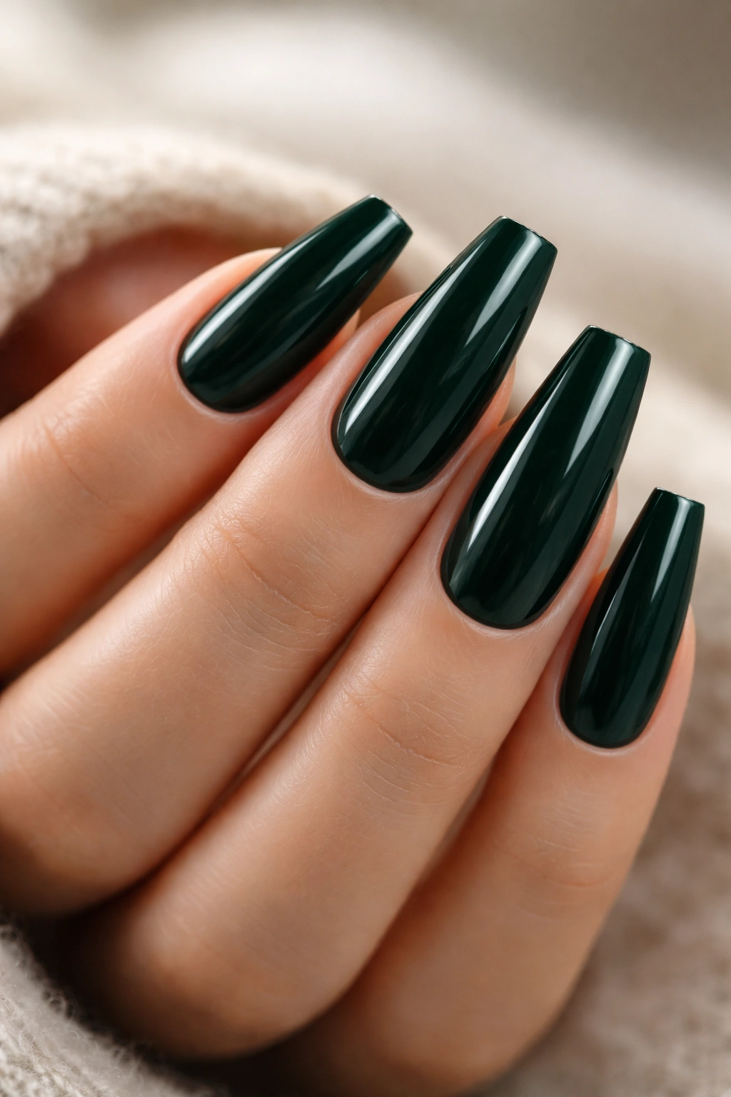 Close-up of dark green coffin nails on a bare hand with a glossy finish