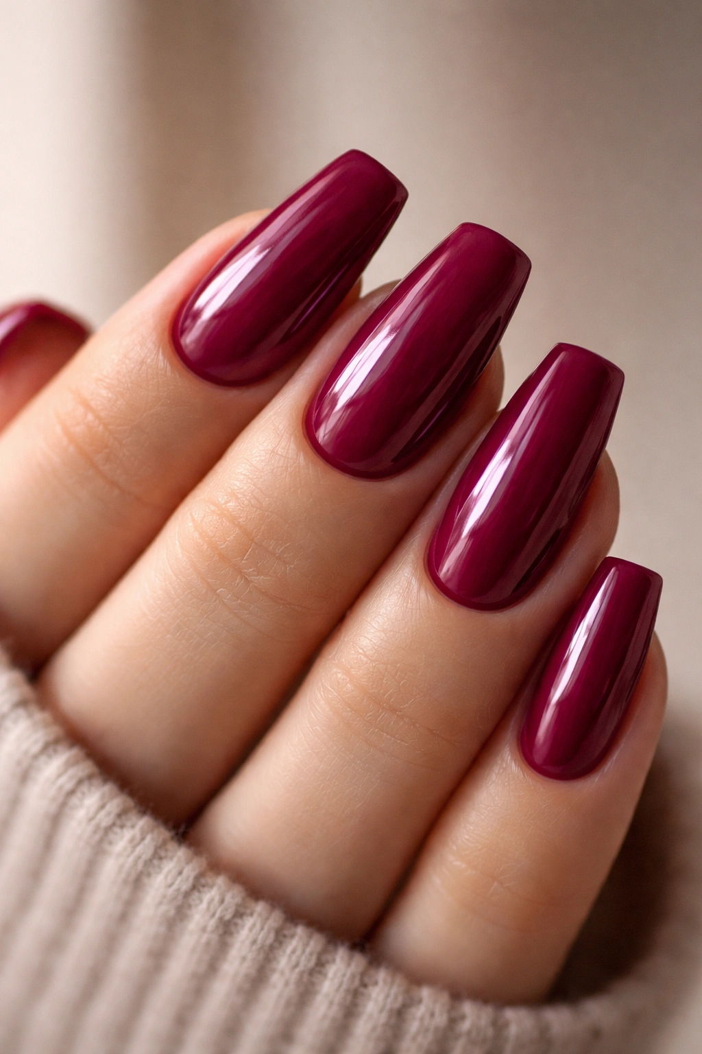 Close-up of coffin nails in deep berry pink with glossy finish on short-to-medium length nails