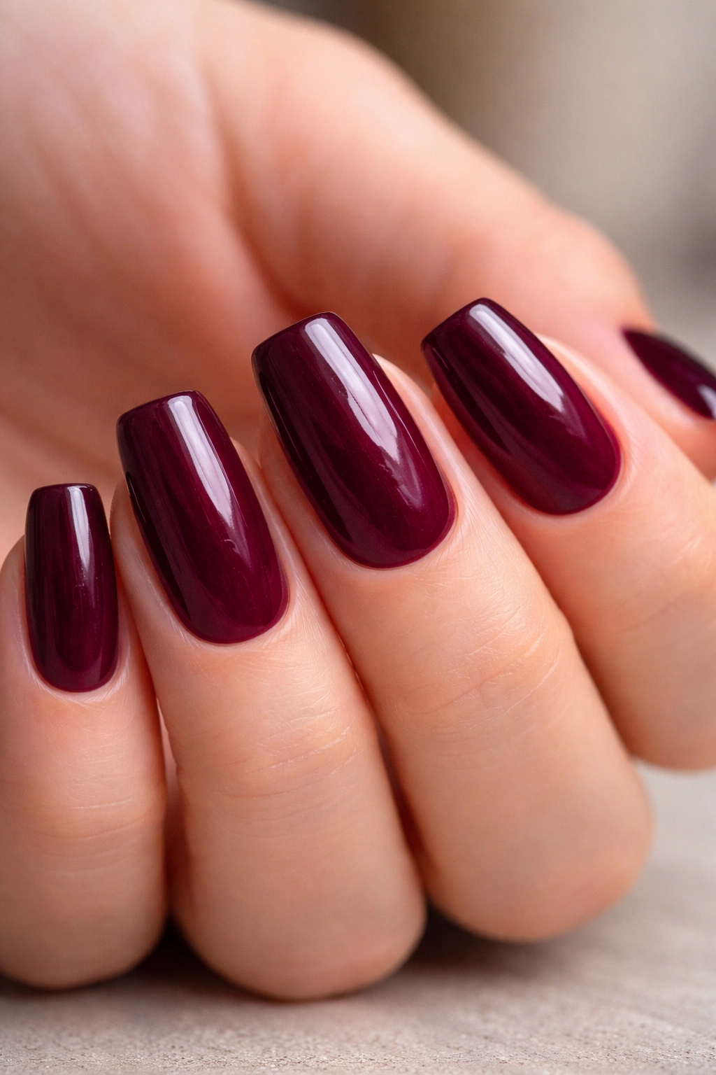Close-up of deep berry wine coffin nails on short length with rich red-purple tones.