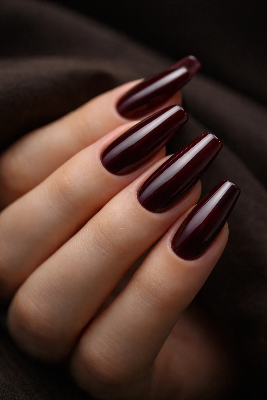 Close-up of deep Bordeaux coffin nails with a cream finish on medium-length fingertips