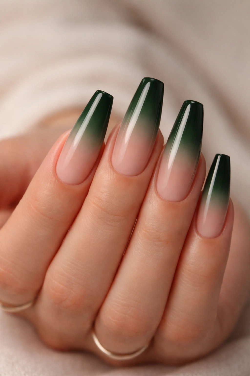 Close-up of coffin nails in sheer nude to deep green ombre