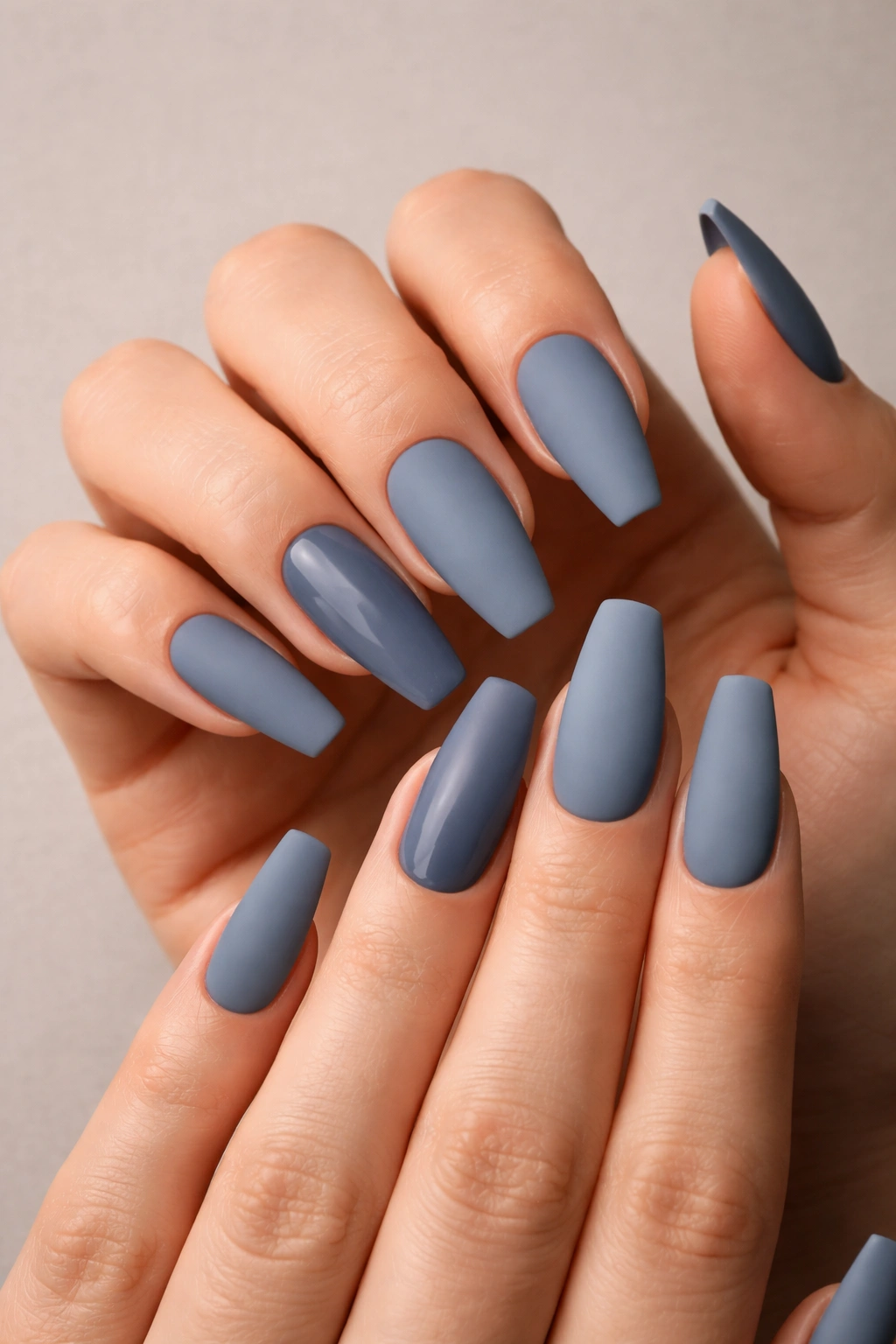 Close-up of dusty denim matte coffin nails on a hand.