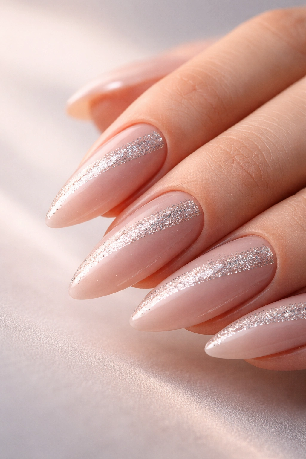 Close-up of almond nails with a diagonal glitter slash on nude base