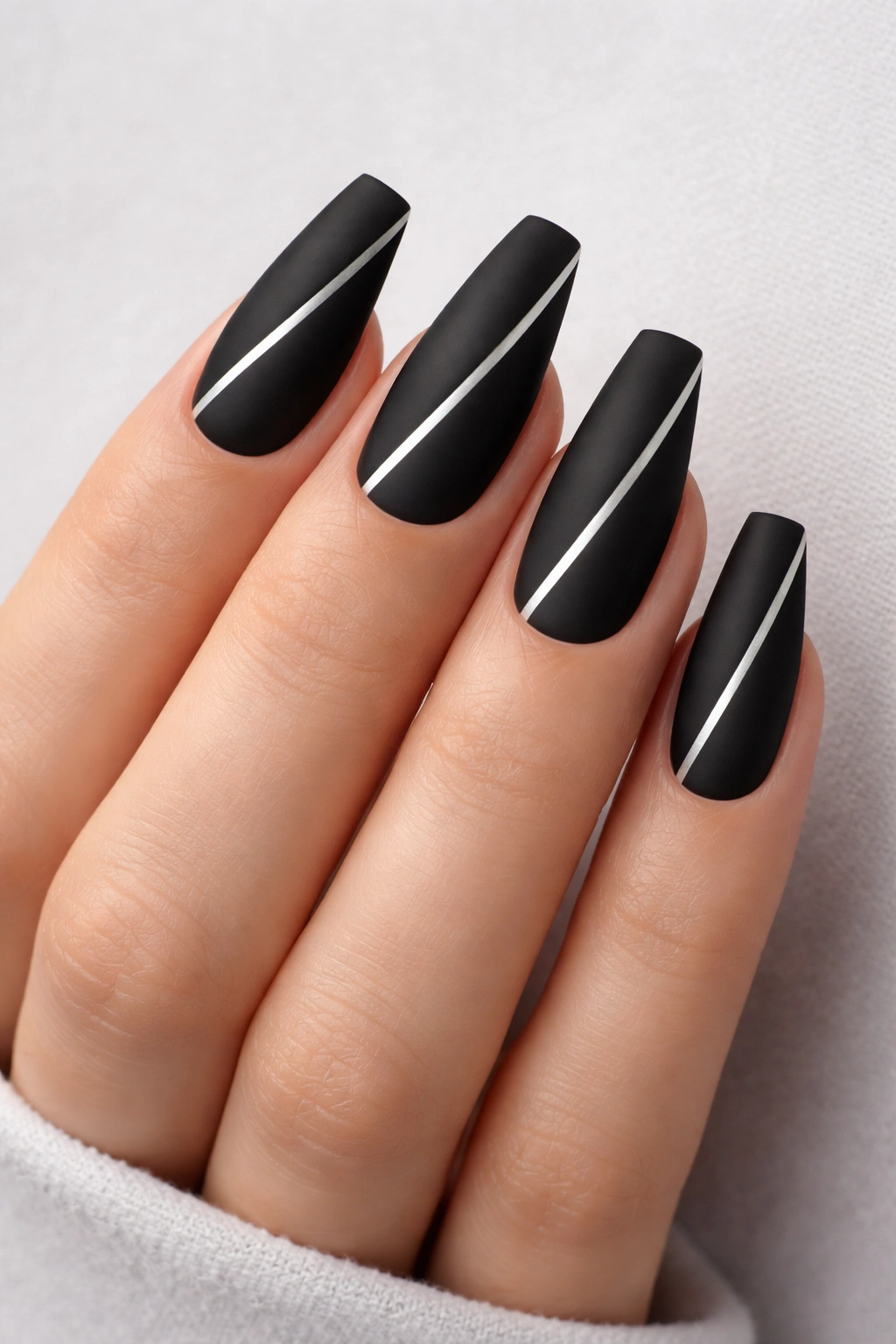 Close-up of matte jet-black coffin nails with a single diagonal silver stripe