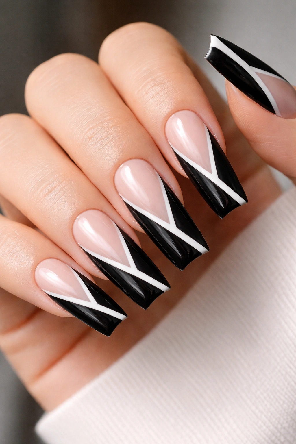 Close-up of coffin nails with diagonal black panels and a thin white stripe on a nude base, glossy finish.