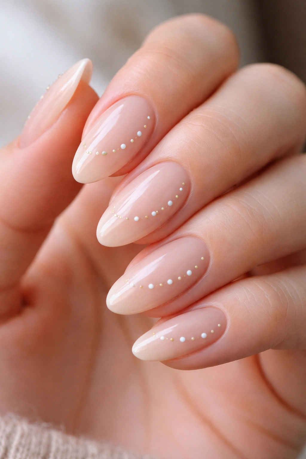 Almond nails with a subtle curved dot trail in nude tones