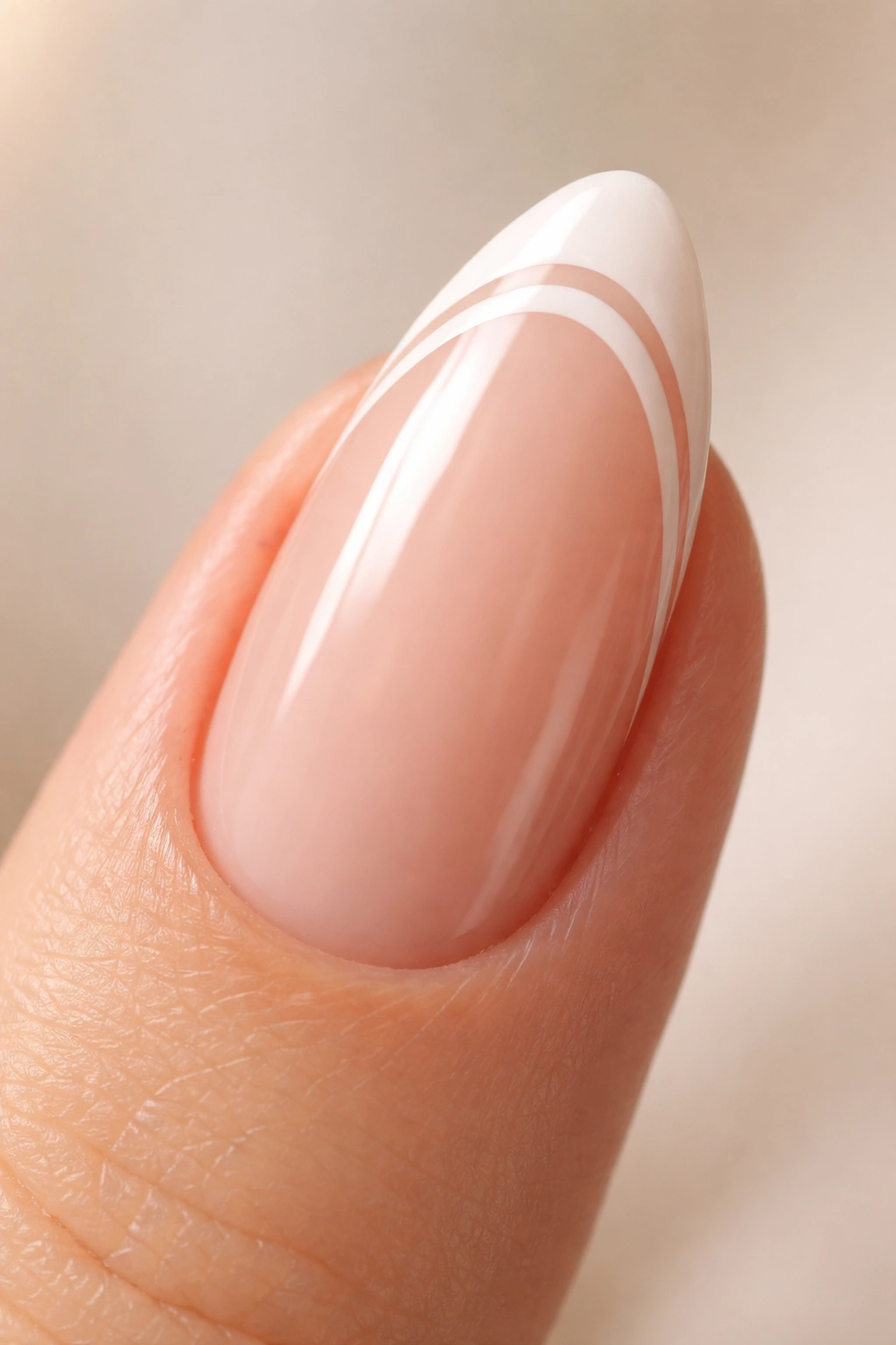 Close-up of an almond nail with two slim white lines near the edge on a nude base
