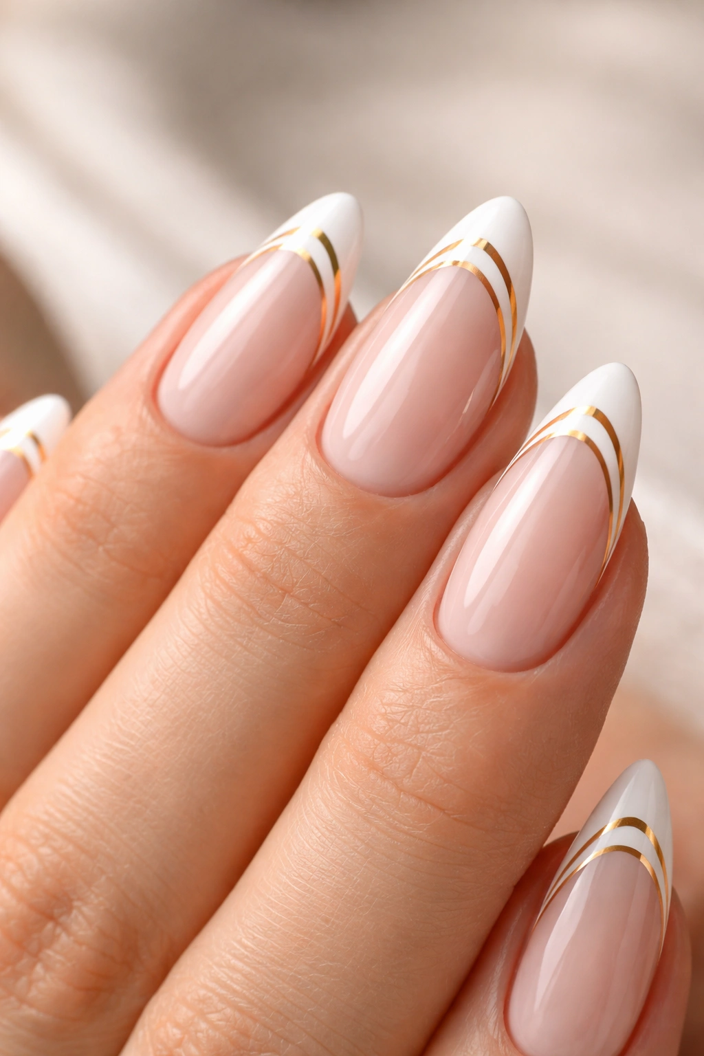 Close-up almond nails with double white and gold tip lines on a sheer base