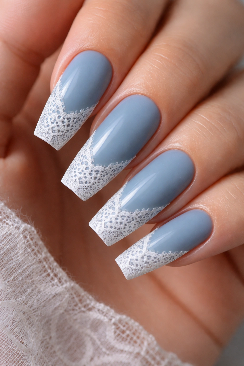 Close-up of coffin nails with dusty blue base and white lace detail.