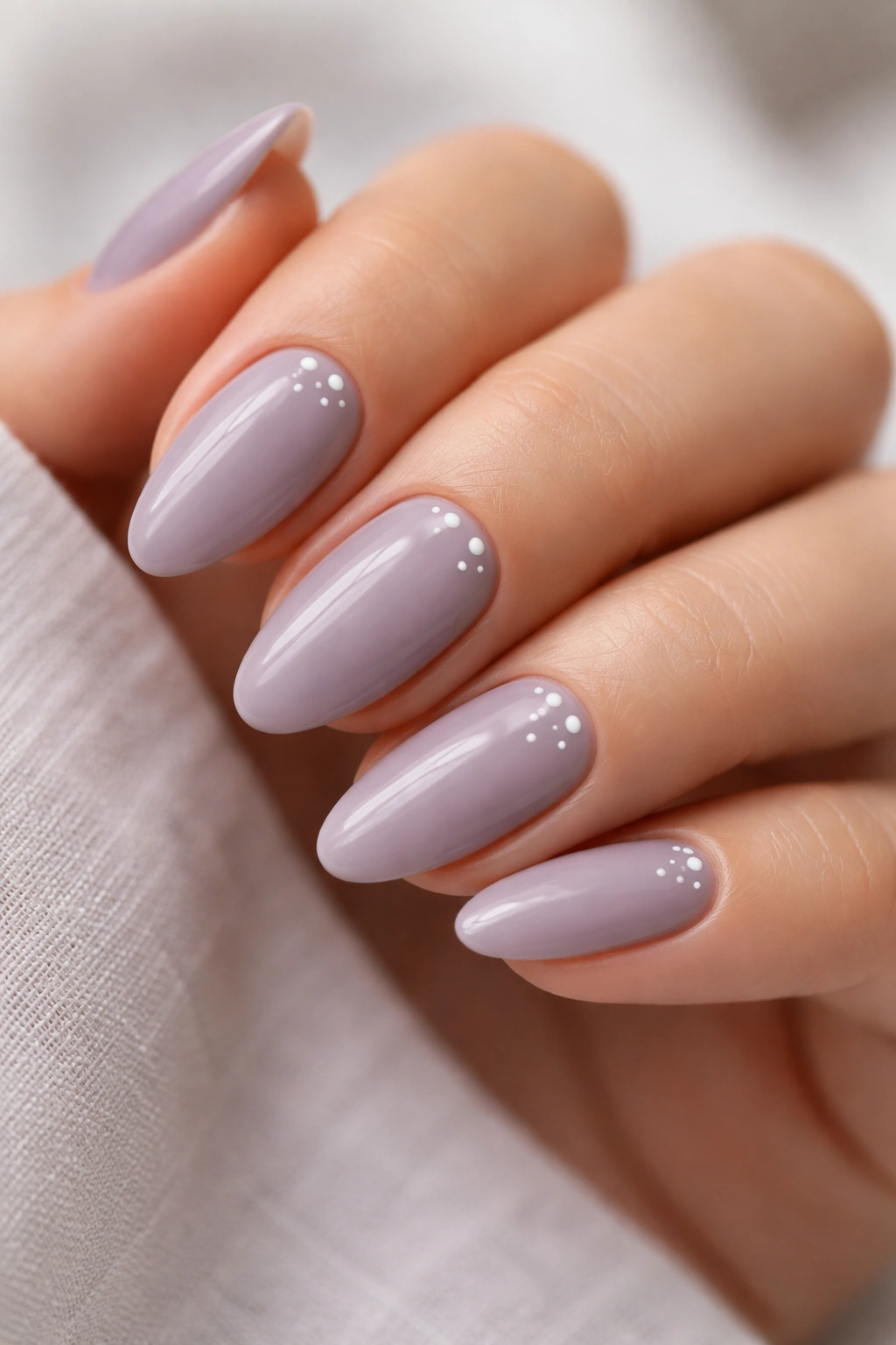 Close-up of dusty lilac almond nails with tiny white dots along the side near the cuticle