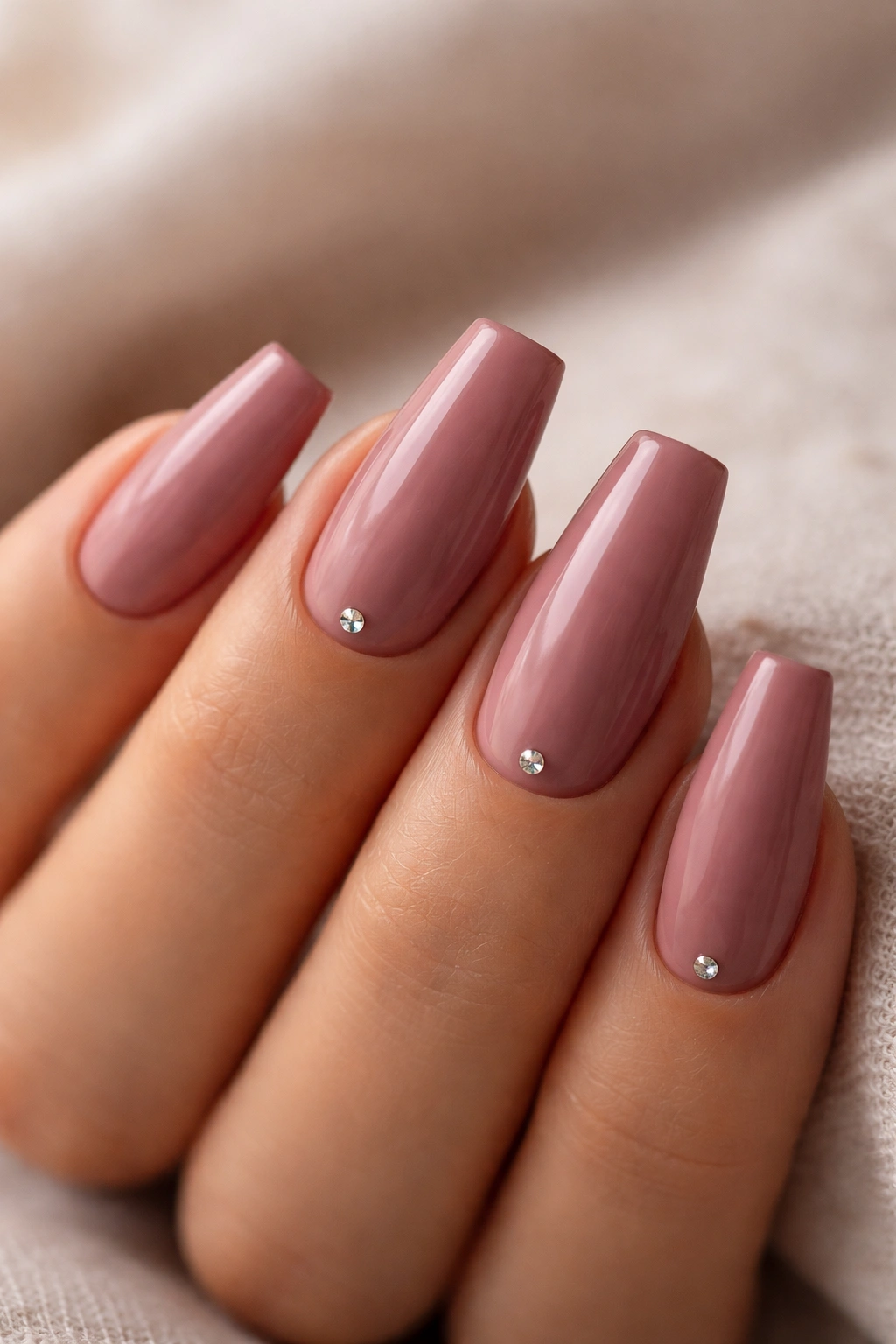 Dusty rose coffin nails with tiny crystal near cuticle