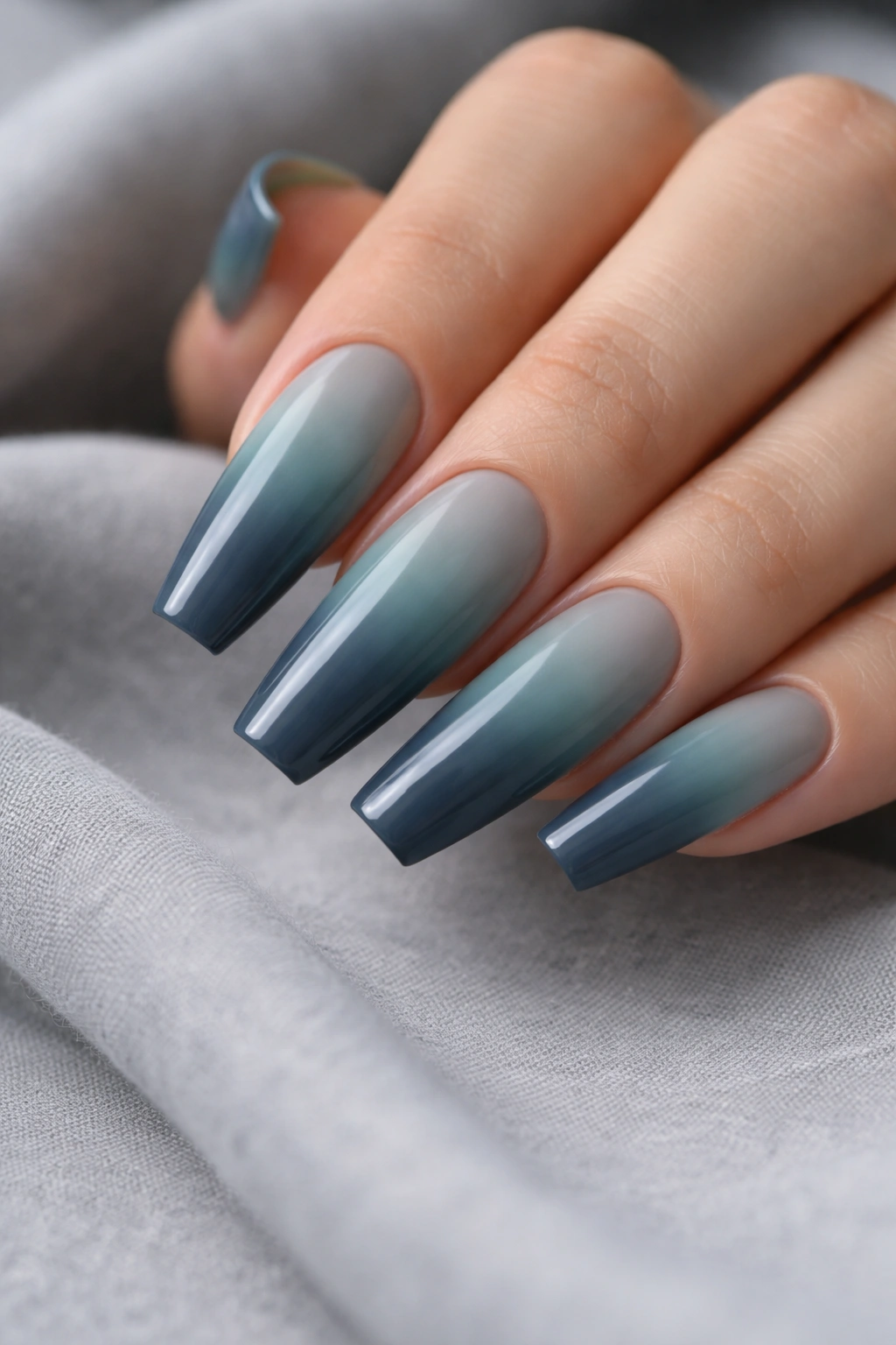 Close-up of dusty teal to slate ombre coffin nails on a hand with glossy finish