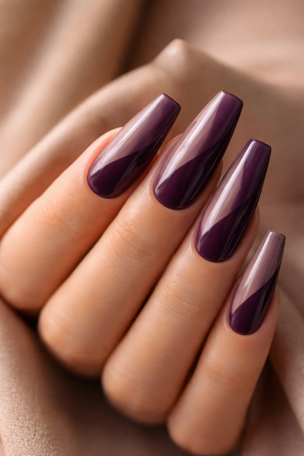 Diagonal eggplant and cocoa coffin nails on a hand