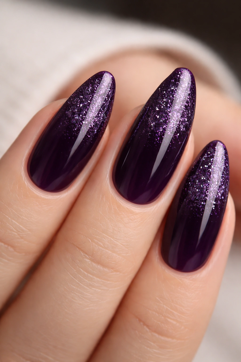 Almond nails with deep eggplant base and fine glitter fade near cuticle.