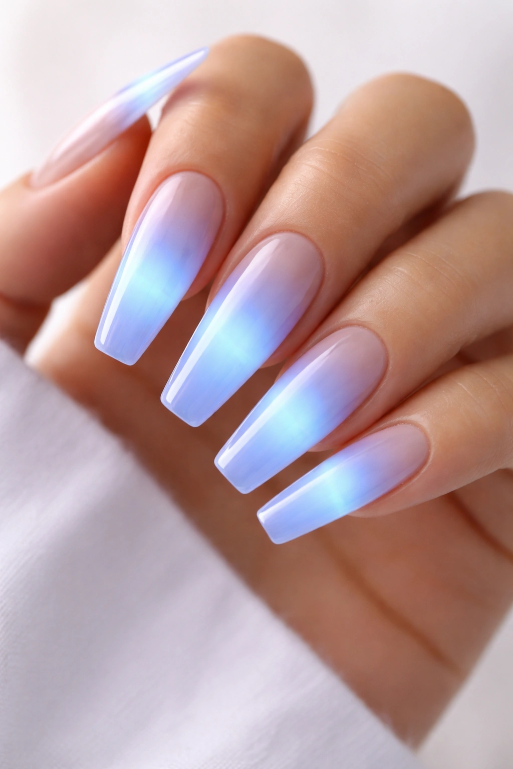 Close-up of long coffin nails with milky base and electric blue aura glow