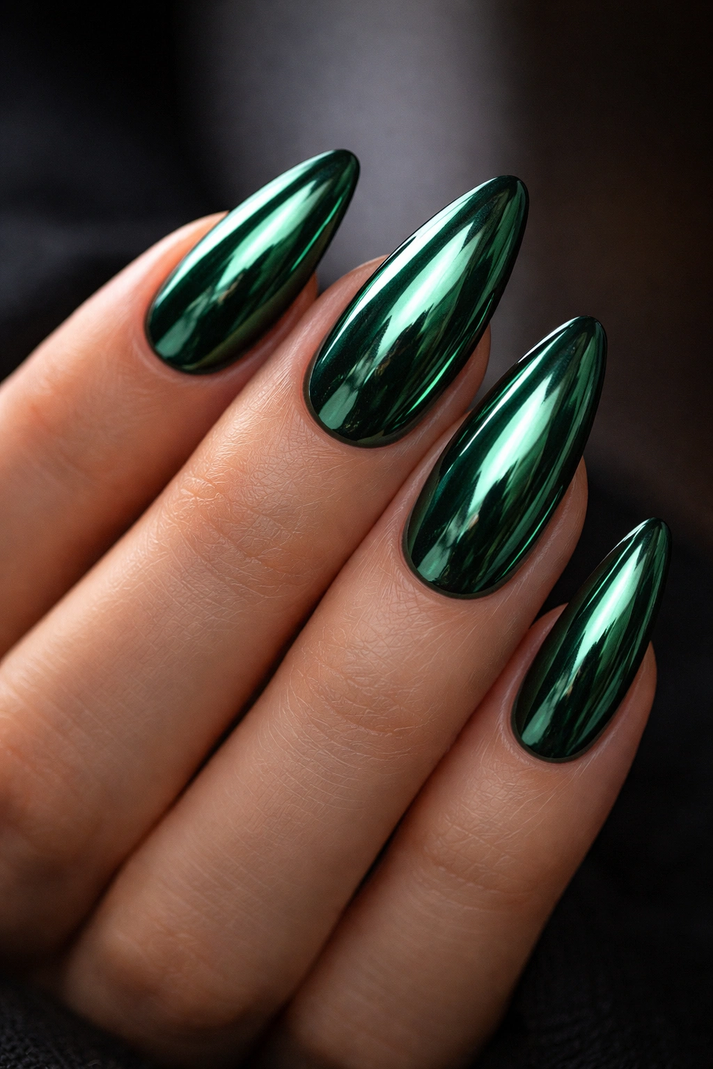 Close-up of emerald chrome almond nails with mirror-like finish.