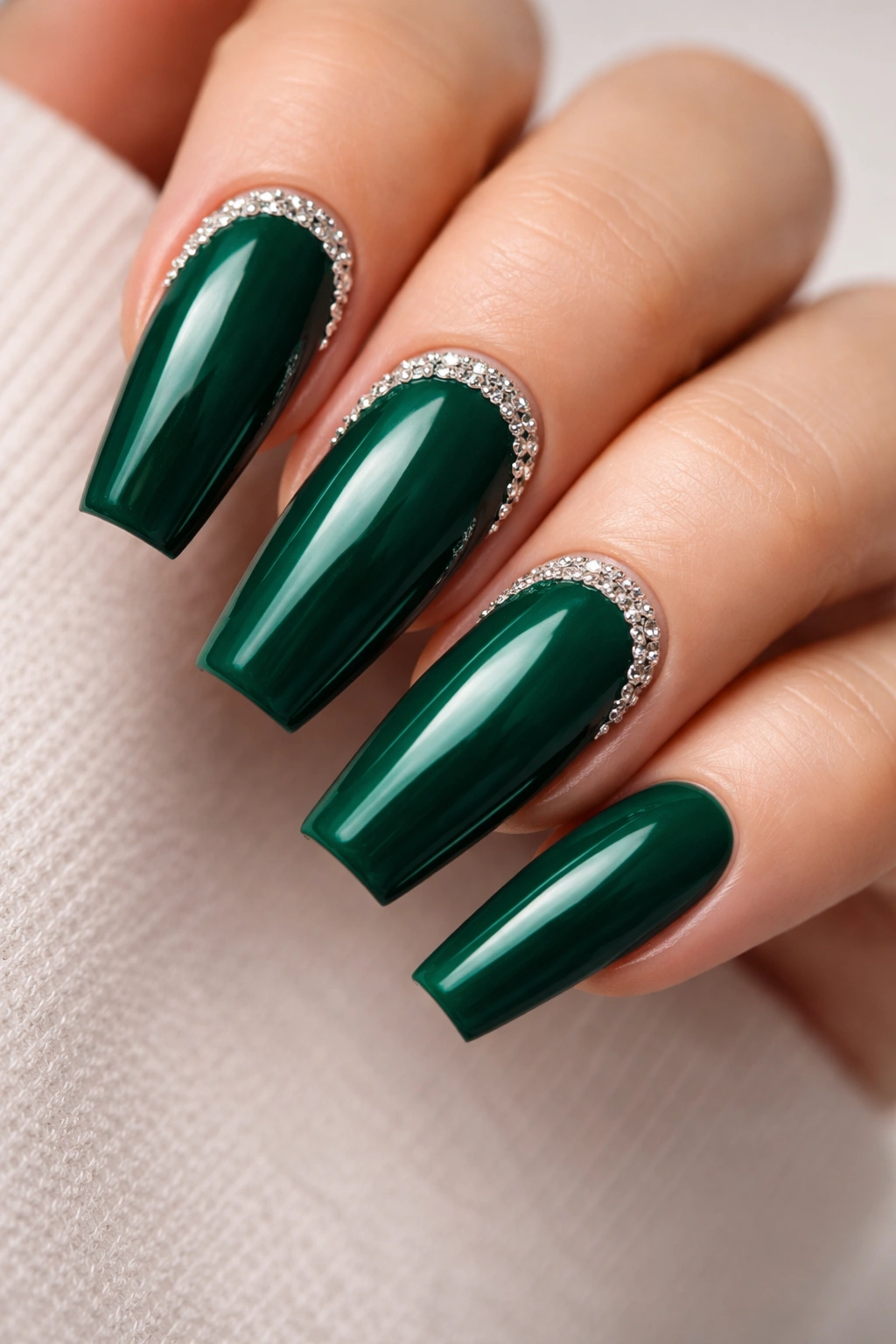 Close-up of emerald green coffin nails with diamond-framed cuticles on a neutral backdrop