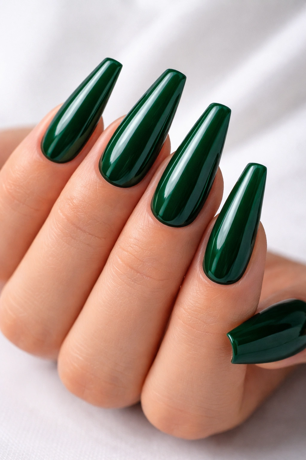 Close-up of glossy emerald green coffin nails on a hand