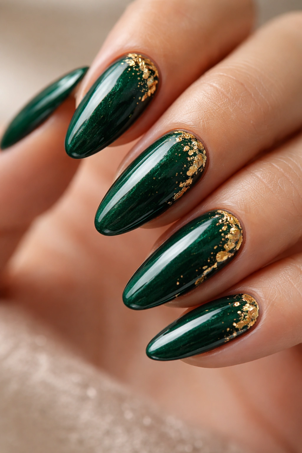 Close-up of emerald nails with small gold foil accents on almond nails.