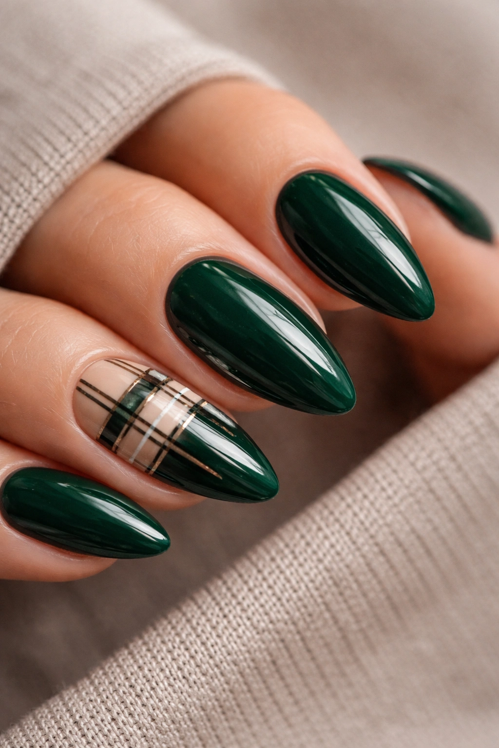 Almond nails in deep emerald with a slim plaid accent on one nail
