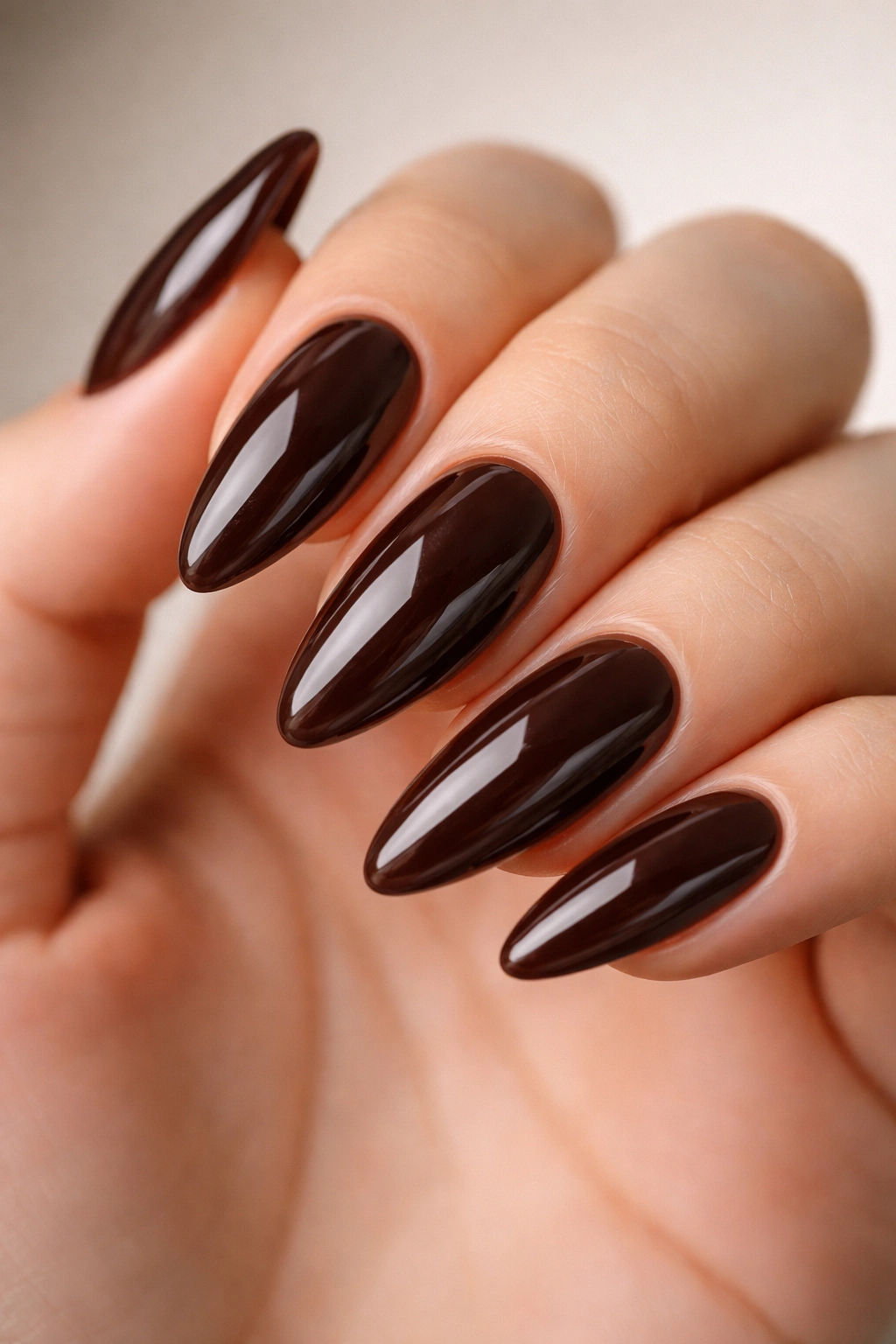 Close-up of deep espresso almond nails on gel extensions with glossy finish