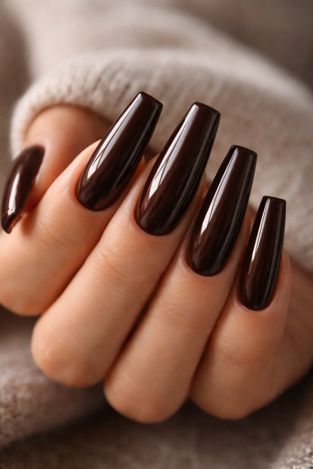 Close-up of long coffin nails painted in espresso brown with cream finish and glossy top coat