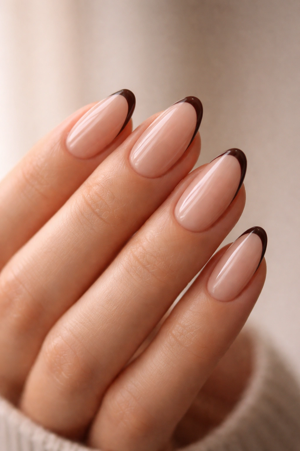 Close-up of almond nails with a sheer base and thin espresso tip