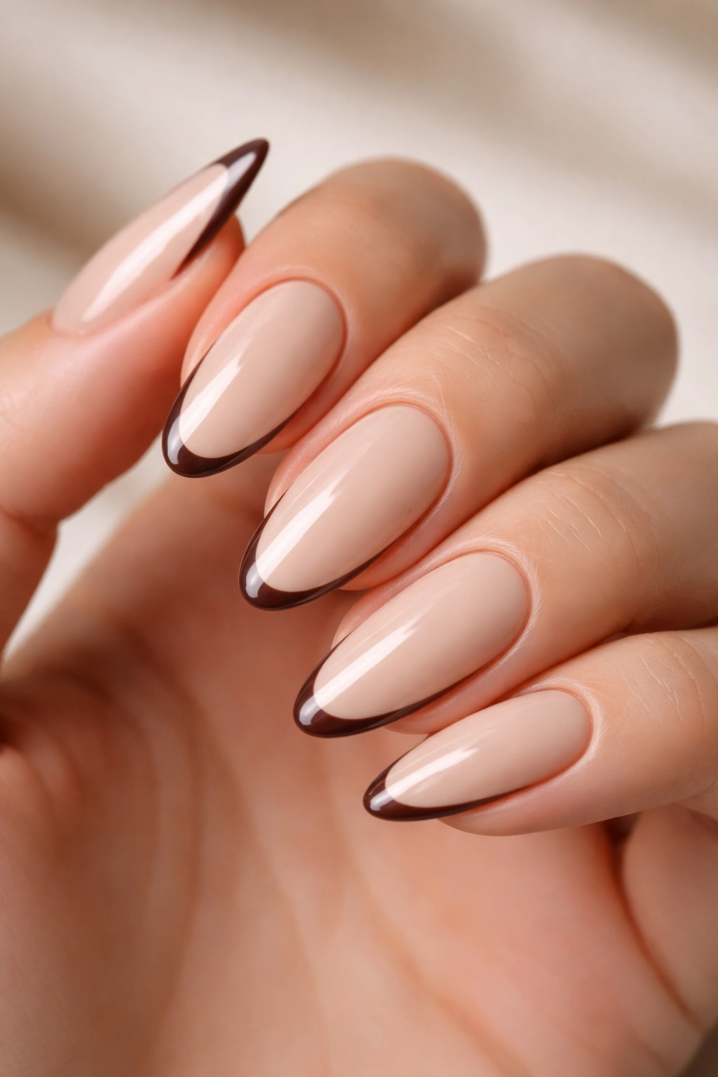 Close-up of espresso outline French on beige almond nails