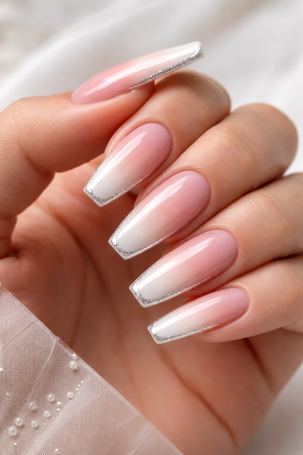 Close-up of coffin nails with a soft pink-to-nude French fade and a slim silver outline.