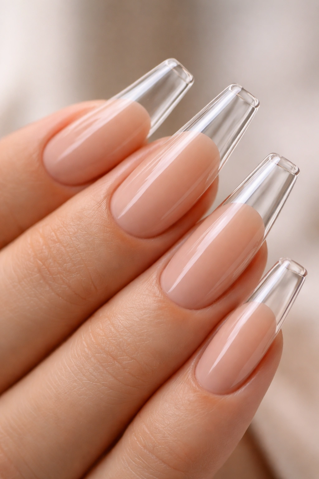Clear glass-like nail tips over a nude nail bed on a hand