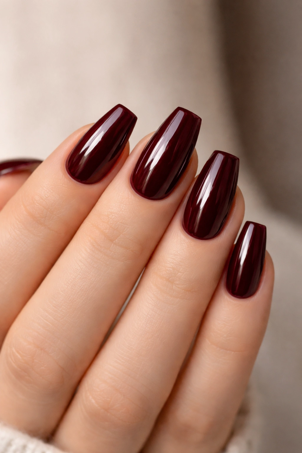 Close-up of short coffin nails with a glassy burgundy finish