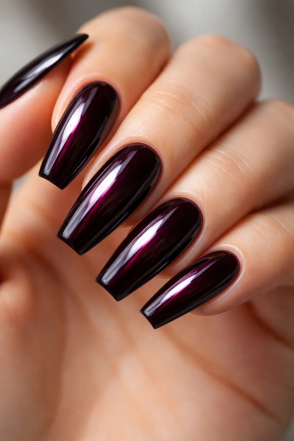 Close-up of glossy black cherry ballerina nails with deep purple depth and high shine