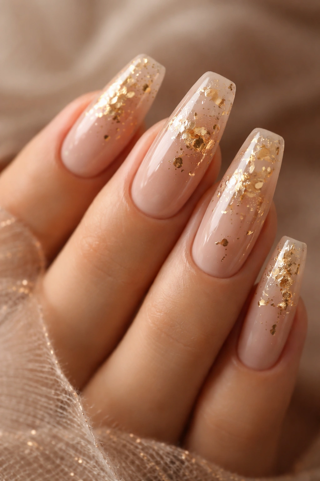 Close-up of coffin nails with nude base and scattered gold foil