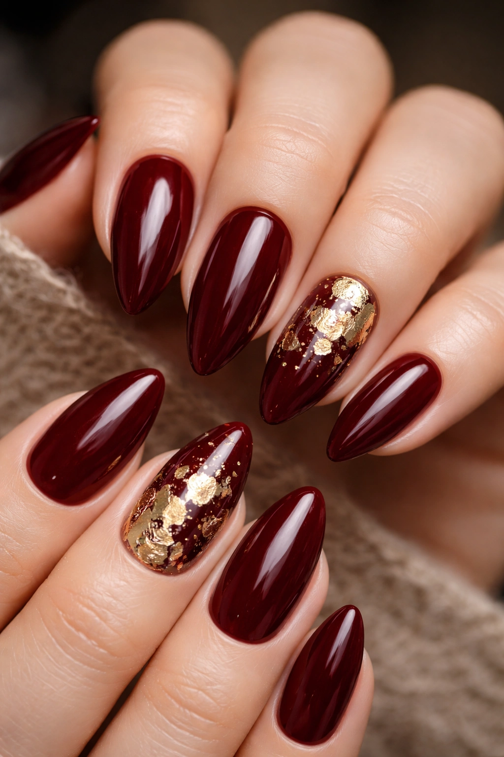 Almond nails with dark red base and gold foil accents