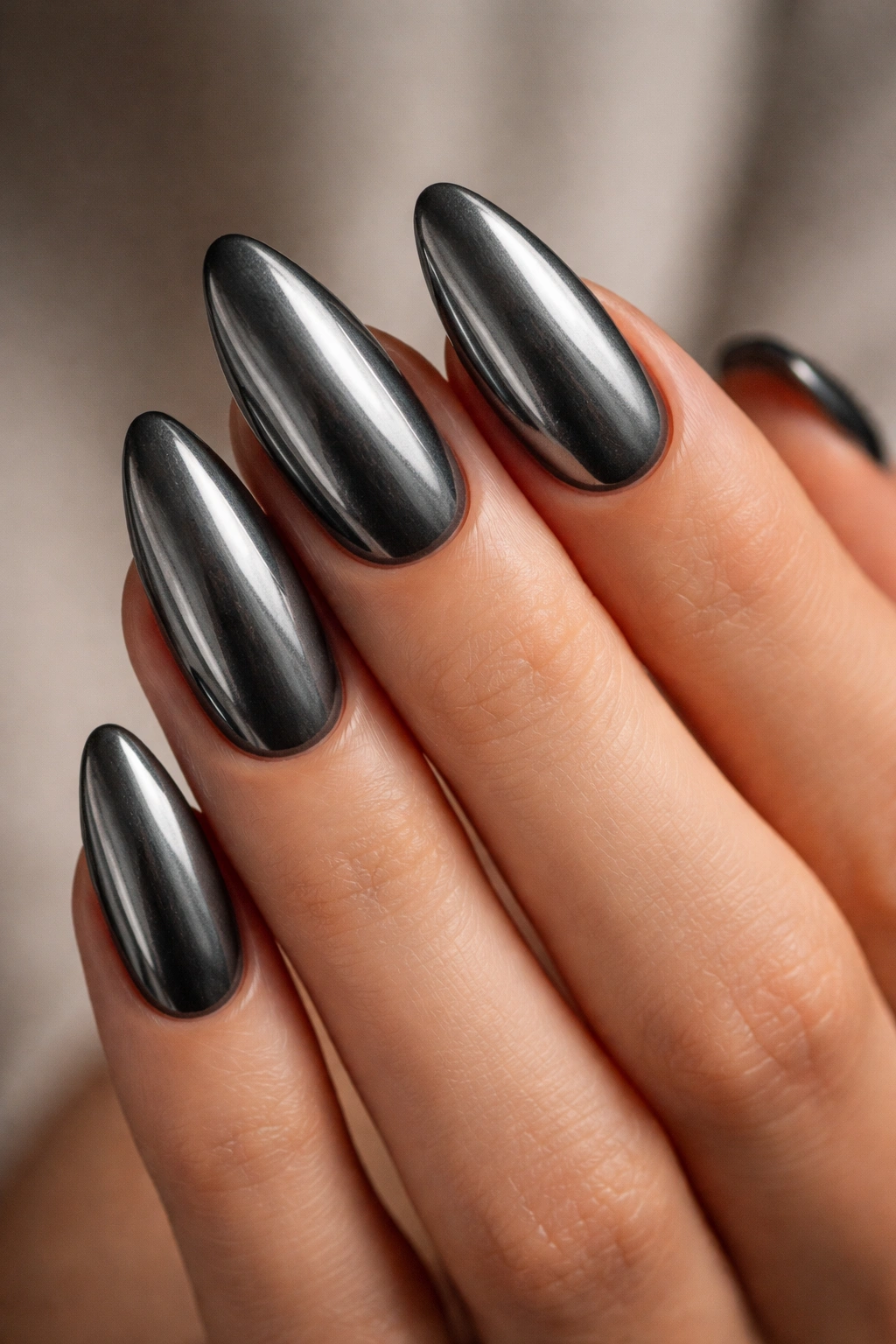 Close-up of graphite chrome almond nails with a charcoal base and brushed-metal shine