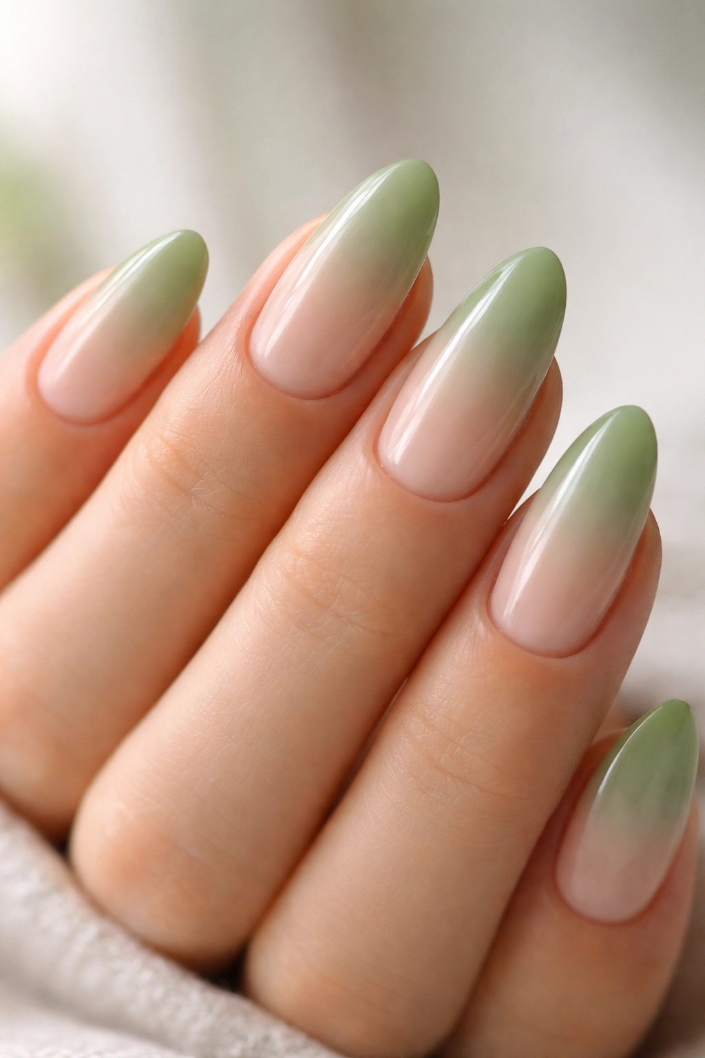 Close-up of green tea ombre almonds nails with sage to green gradient