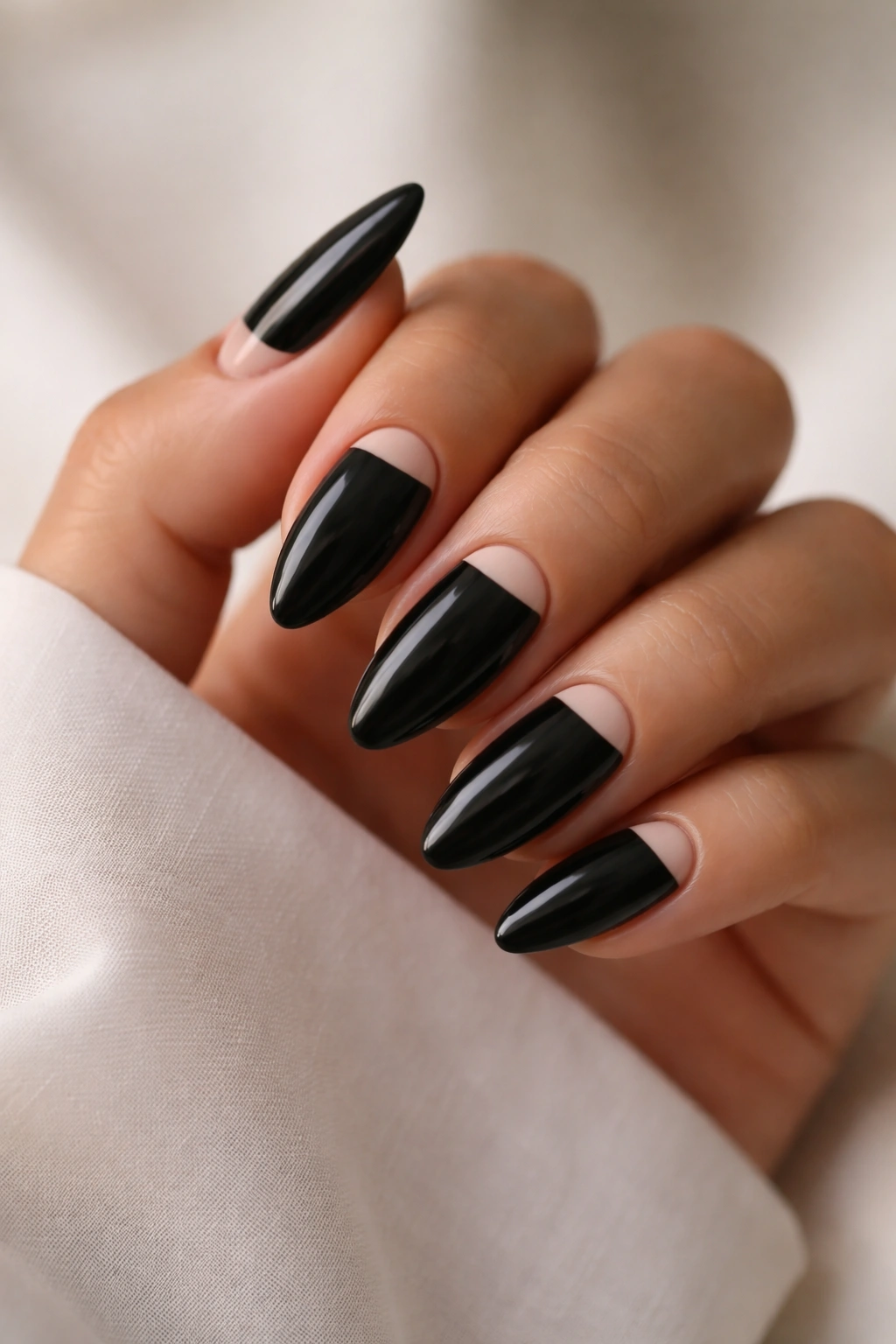 Almond nails with black polish and a slim light half-moon at base