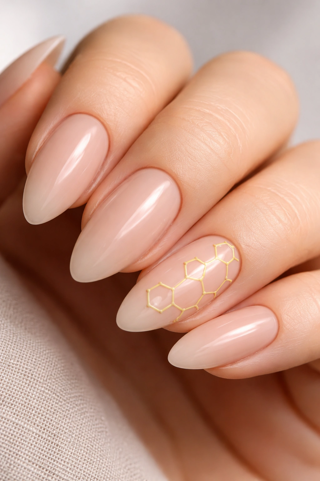 Nude almond nails with yellow honeycomb line art on an accent nail